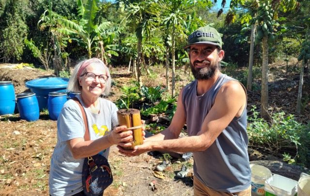 A moradora recebe sua muda das mãos do Daniel - Fotos Prensa de Babel