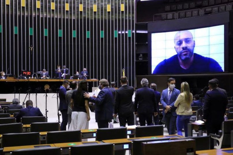 Na sessão da tarde desta sexta, Daniel Silveira discursou na sessão da Câmara, em participação por vídeo, a partir do Batalhão Prisional da Polícia Militar, no Rio de Janeiro.

O parlamentar teve quinze minutos para expor sua posição. Ele fez um "mea culpa", definindo seu vídeo com críticas e ameaças aos ministros do STF como sendo um "excesso" ou "exagero"/ Foto reprodução vídeo Câmara Deputados
