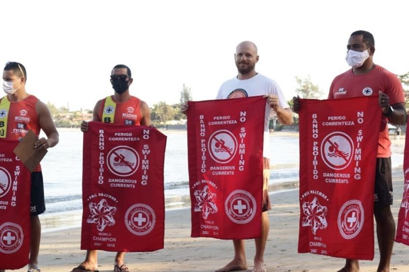 Na praia de Geribá, Phil Rajzman entrega as bandeiras aos guarda-vidas de Búzios. Imagem: Divulgação