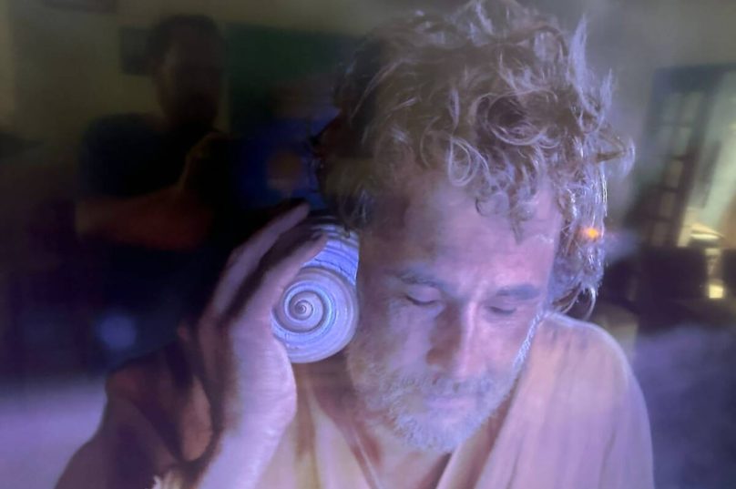 Rodrigo Santoro segura um búzio encostado ao ouvido em cena filmada em Búzios para O Filho de Mil Homens, produção já disponível na Netflix - Imagens reprodução Ntflix